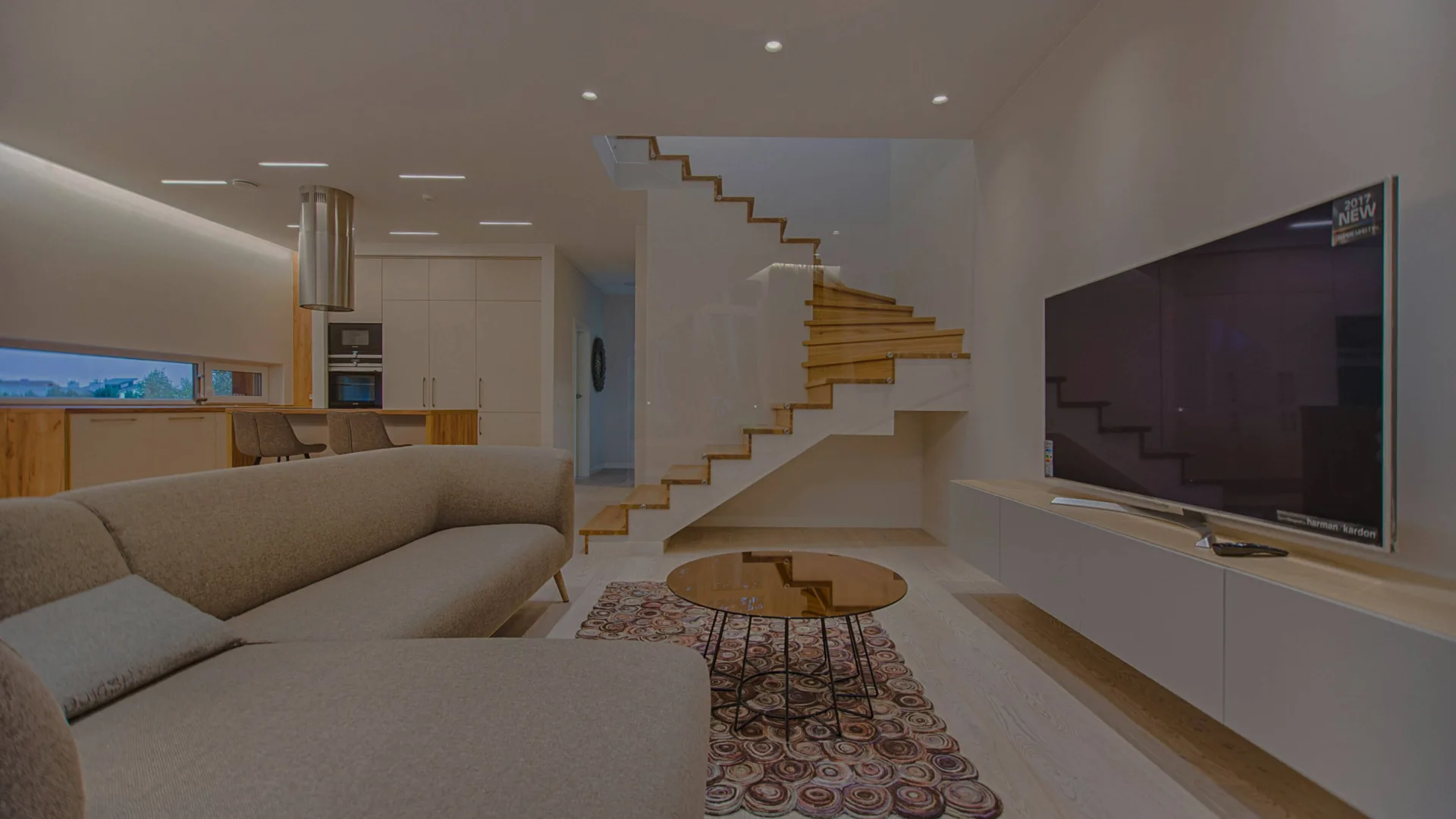 Modern living room with sofa, TV, and staircase.